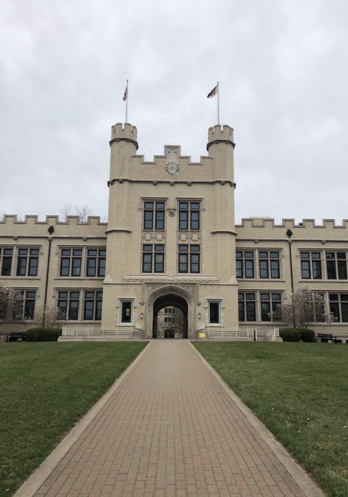 Kauke Hall; a castle like building with two flags and an archway. A brick pathway leading up.